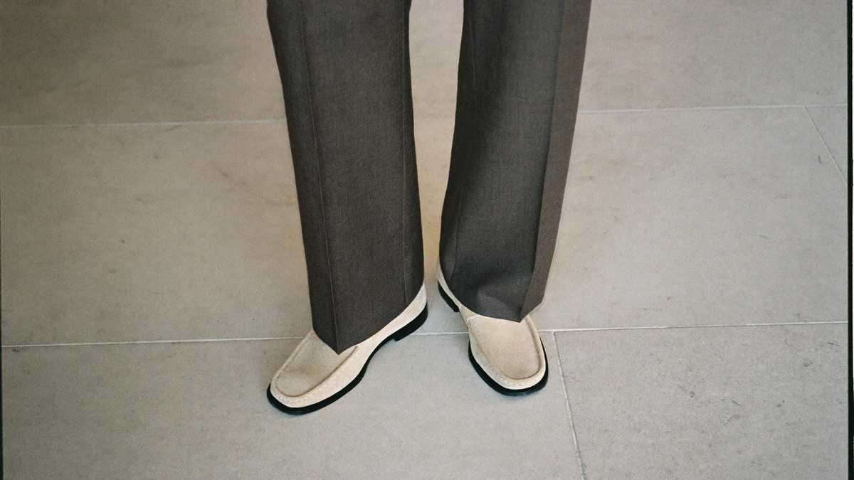 Charcoal tailored trousers falling with a clean single break over sand suede loafers